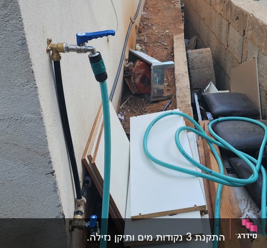 ברז מים עם צינור ירוק מחובר לקיר